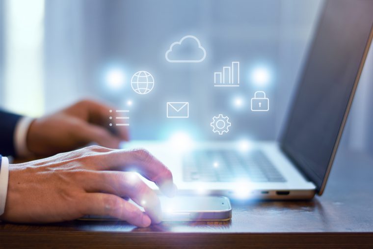 パソコンを操作するビジネスマンと各種クラウドアイコン